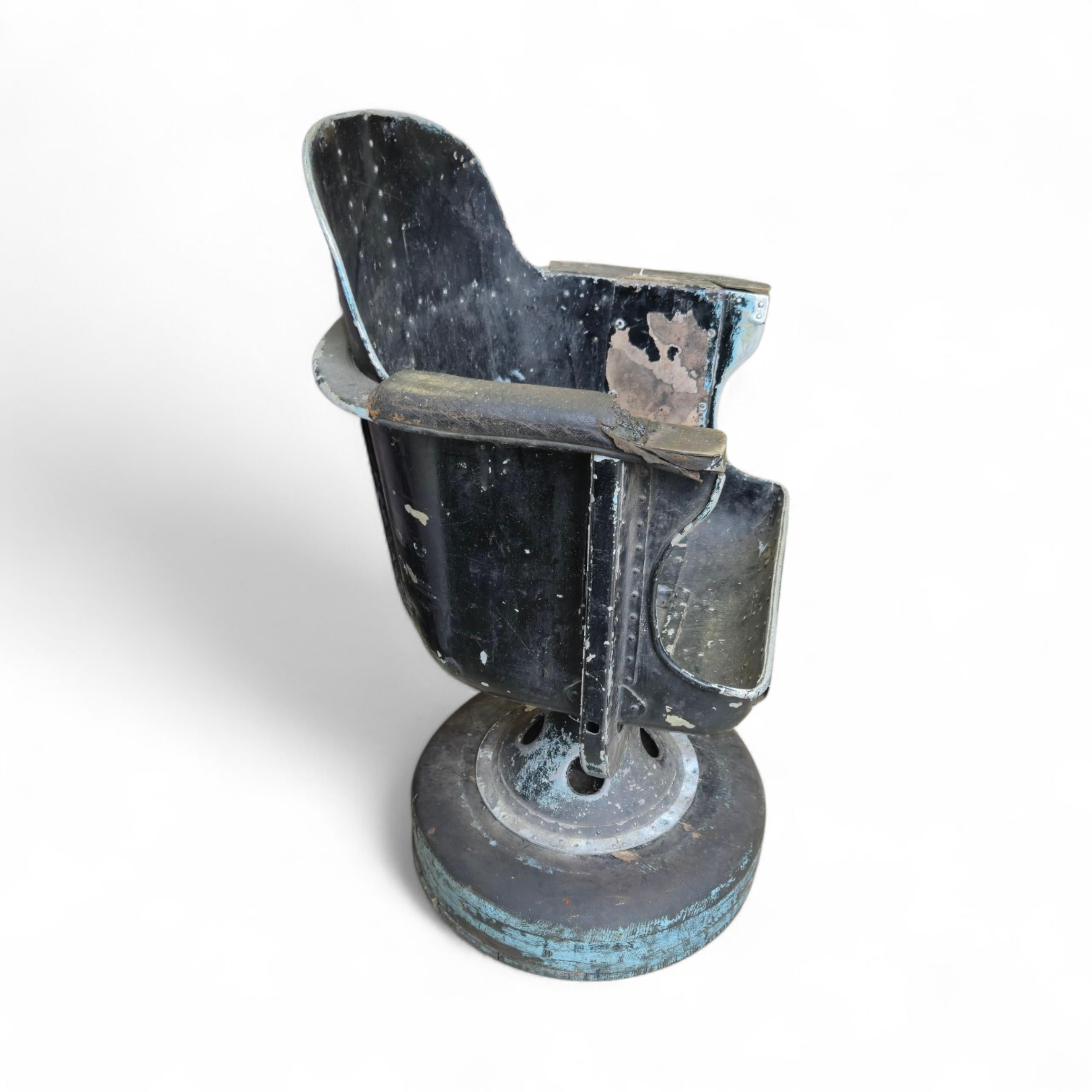 A WWII bomber navigator's chair, with painted aluminium bucket seat and pedestal stand, with a later wooden base, height without base 84cm, the width across the arms 59cm